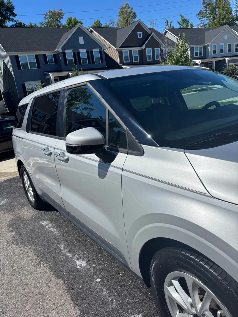 Silver Kia Carnival in profile on a driveway, paint washed and windows cleaned
