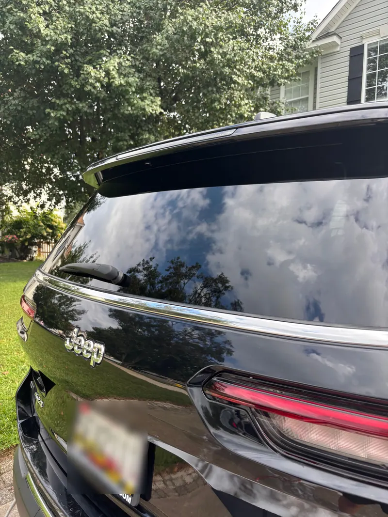 Rear tailgate of a black Jeep Grand Cherokee reflecting the sky after polishing