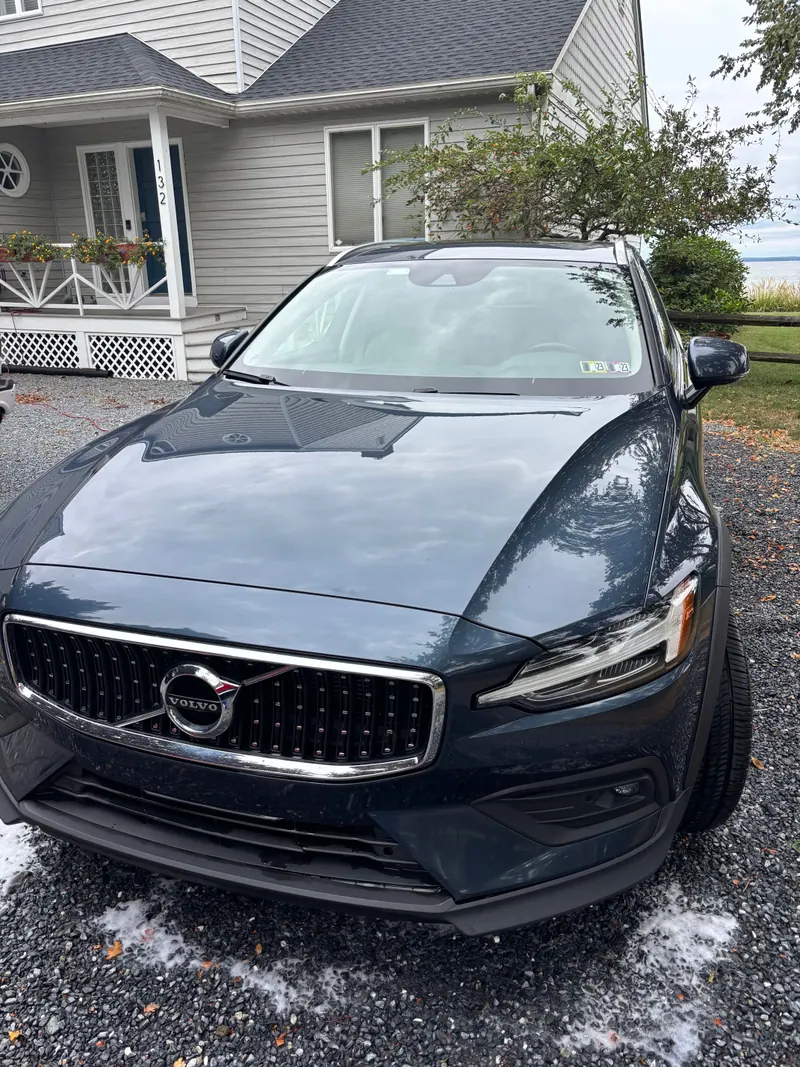 Dark blue Volvo V60 wagon head-on in a driveway, paint polished to a mirror finish