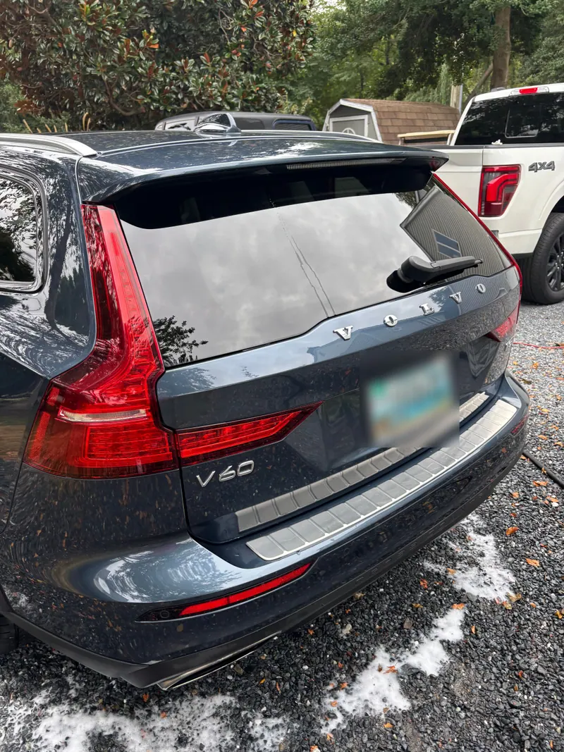 Rear of a dark blue Volvo V60 wagon, tailgate and chrome trim polished