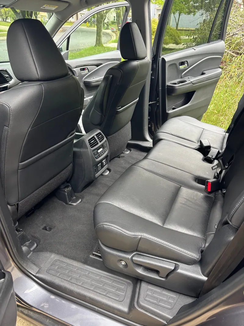 Rear seats of the Honda Pilot in black leather with floor liners cleaned